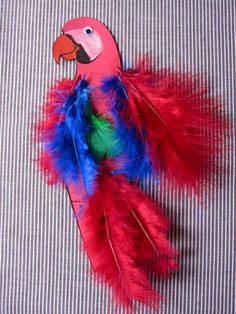 a red and blue bird with feathers on it's back sitting on a bed