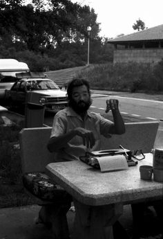 a man sitting at a table in front of a laptop computer