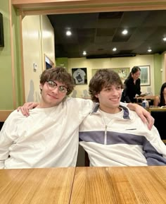 two young men sitting next to each other at a table