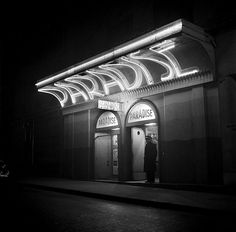 a black and white photo of a building at night with neon lights on the front