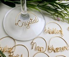 some wine glasses with names on them sitting next to flowers