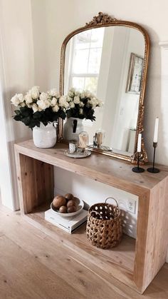 a wooden table topped with a mirror next to a vase filled with flowers and eggs