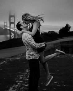 a man and woman are kissing in front of the golden gate bridge