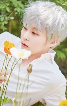 a man with white hair holding flowers in his hand