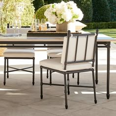 an outdoor dining table and chairs with flowers in vases on the top one side