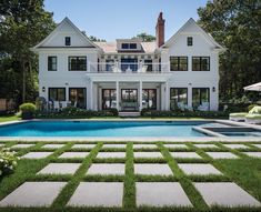 a large white house with a pool in the front yard and grass on the lawn