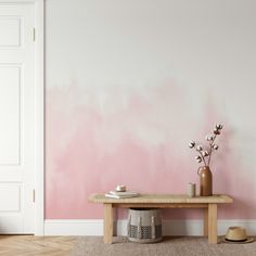 a pink and white painted wall in a living room next to a wooden table with vases on it