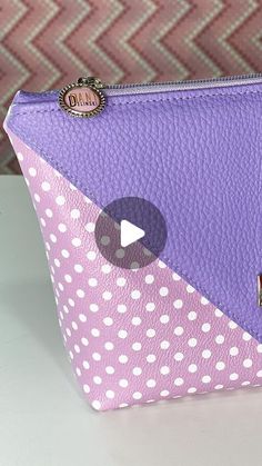 a purple and white polka dot purse with a video playing button on the front side