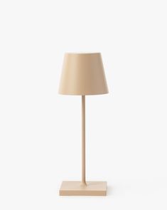 a lamp that is on top of a wooden stand with a beige shade over it