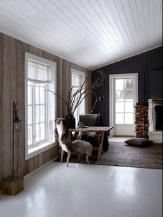 a living room with wood paneling and two windows in the wall, along with a rug on the floor