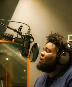 a man with headphones is in front of a microphone and recording equipment, listening to music