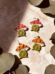 six small animal shaped earrings sitting on top of a leafy table next to a plant