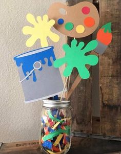 a mason jar filled with lots of crafting supplies on top of a wooden table