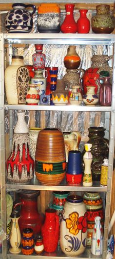 a shelf filled with lots of colorful vases on top of metal shelving units