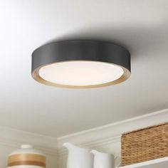 a black circular light fixture hanging from the ceiling in a room with white walls and wicker baskets