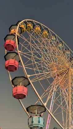 an amusement park ferris wheel with colorful seats on it's side and the sky in the background