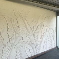 the wall is painted with white paint and has large leaves on it's side