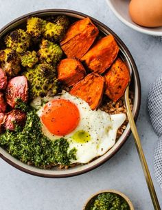 a bowl filled with eggs, broccoli and other food on top of a table