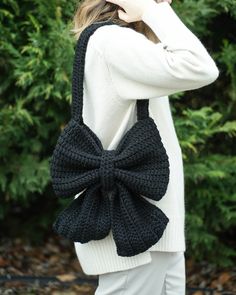 a woman wearing a black crochet bow bag