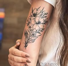 a woman's arm with flowers and leaves tattooed on the left side of her arm