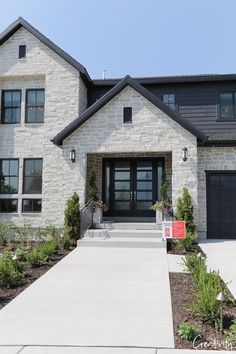 a large white house with black garage doors and windows on the front door is shown