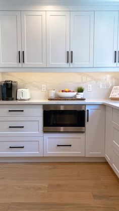 a kitchen with white cabinets and wood flooring, including an oven in the center