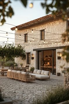 an outdoor seating area with patio furniture and string lights strung from the house's roof