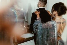 a man and woman standing in front of a mirror