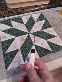 someone is making a snowflake quilt on the counter top with a sewing needle