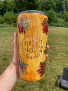 a person holding up a wooden cup in their hand with the words fall written on it