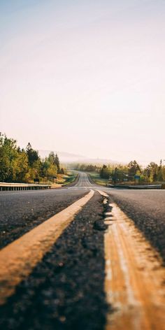 an empty road with two lines painted on the side and trees in the back ground