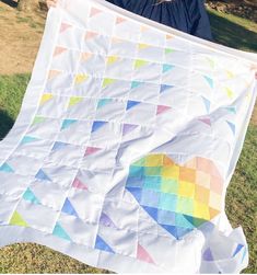 a woman holding up a large white quilt