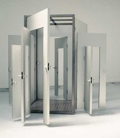 an open white room with multiple doors on each side and four stalls in the middle