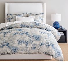 a bed with blue and white comforter in a bedroom next to a night stand