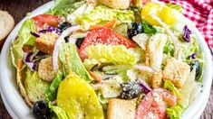 a salad with croutons, tomatoes, lettuce and olives in it