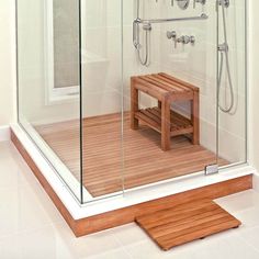 a wooden bench sitting in front of a glass shower