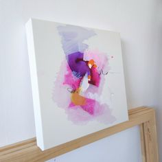 a painting is hanging on the wall next to a wooden framed object with an orange and pink abstract design