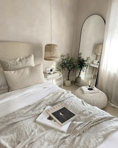 a bed with white linens and pillows in a bedroom next to a mirror on the wall