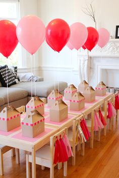 some pink and red balloons are in the shape of castle boxes on top of a table