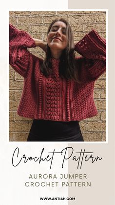 a woman wearing a red sweater standing in front of a brick wall with her hands on her head