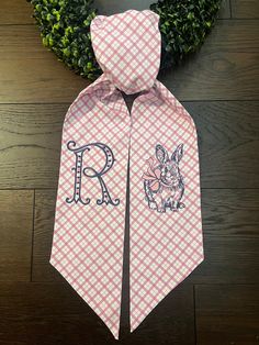 a pink and white gingham neck tie with the letter r on it's side