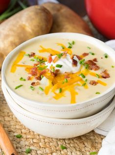 a white bowl filled with potato soup and topped with bacon, sour cream and green onions