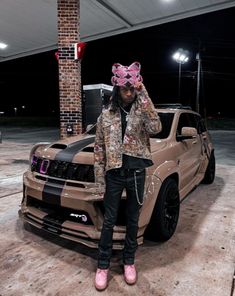 a person standing next to a car with a pink bow on it's head