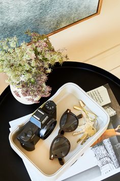 a tray with sunglasses and other items sitting on it next to a potted plant