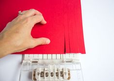 a person is cutting out red paper with scissors