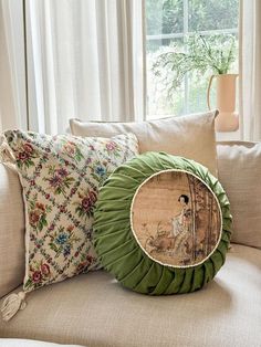 two pillows sitting on top of a couch next to a window