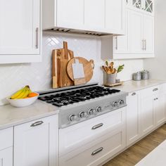 a kitchen with white cabinets and counter tops, including a stove top oven in the center