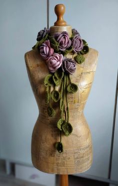 a wooden mannequin with crocheted flowers on it's back and neck