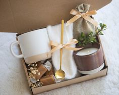 an open box with candles, coffee mug and other items