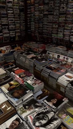 many magazines are stacked on top of each other in a room filled with books and magazines